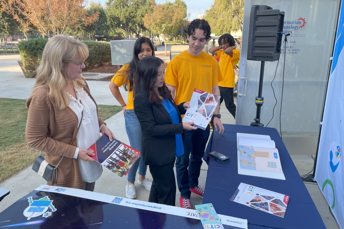 photo of Bao with Interns infront of the bulldog backdrop holding program CITY flyer in Mckee office