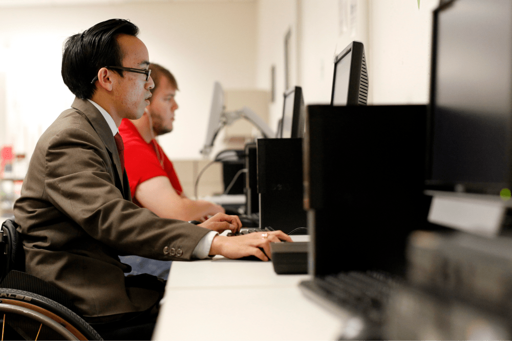 Man in wheelchair looking at monitor in a computer lab