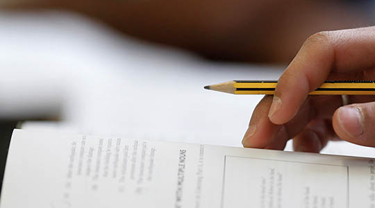 close up of a hand holding a pencil and filling out a form