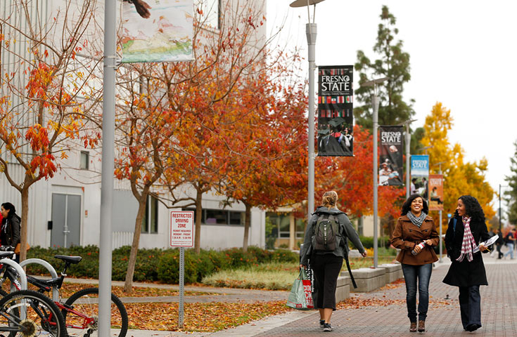 Students walking in front of the library in fall